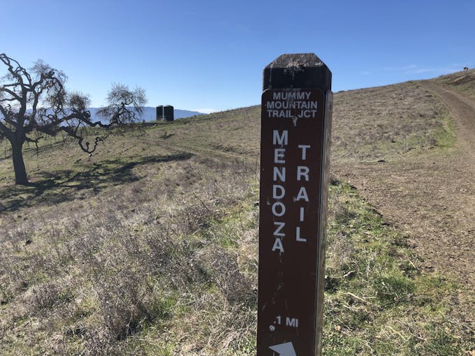 Trail marker near the fork between two wide trails entitled 