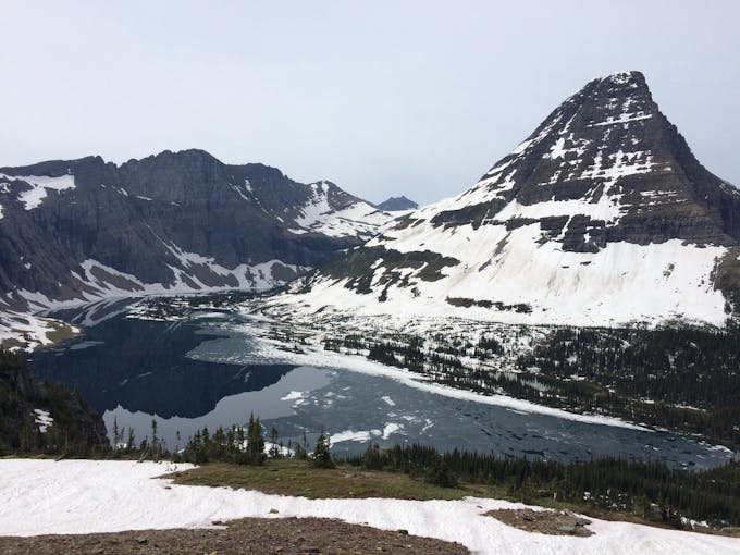 Tall snow-covered mountains fill the background. A river flows in front of them.