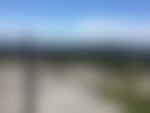 A signpost for trails on a rocky mountain. There are other peaks and blue skies in the background.