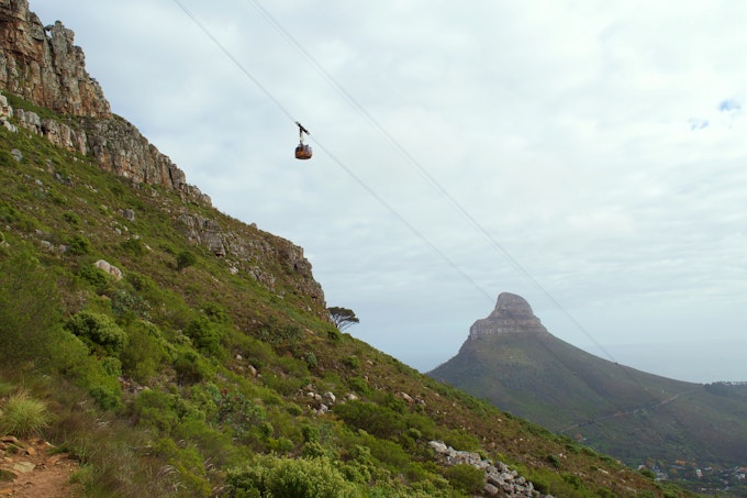 Cable car going up wire with mountain in background