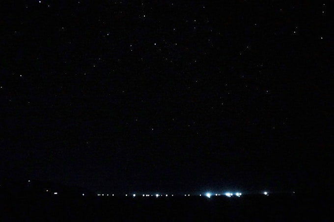 Starry sky with lights from fishing boats on the horizon