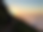 clouds at sunset surrounding mountain top with two hikers