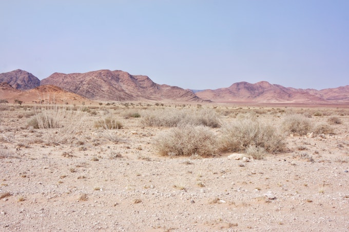 Pastel mountains in the background with sand and sagebrush in foreground.