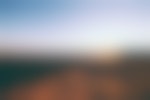 Two hikers are silhouetted on the rocky outcropping against the setting sun