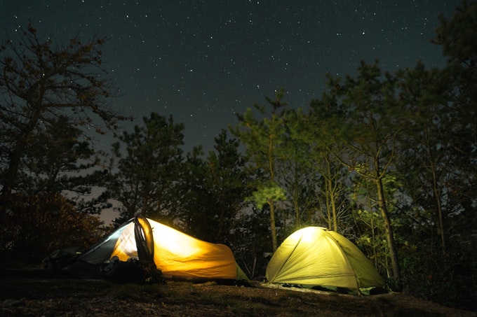 Two tents are lit up against the night