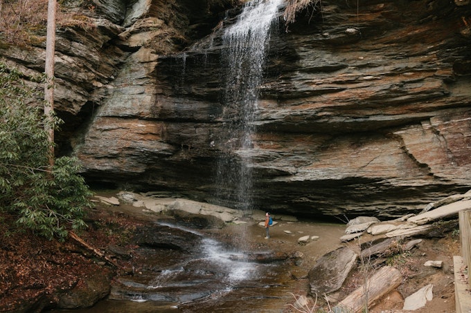 a waterfall tumbles out of a hole in the cliff and splatters the ground