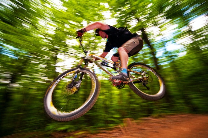 A mountain biker takes a jump on the trail