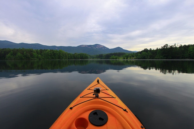 A kayak glides through a glassy, calm lake