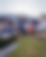 Two parents and three little kids sitting on lawn chairs in front of a large tent. There is a small shaggy dog in the grass.