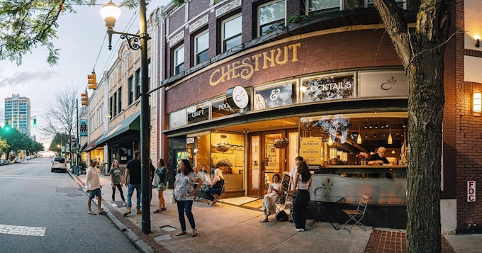 A street view of the exterior of an eatery with a sign that says, 