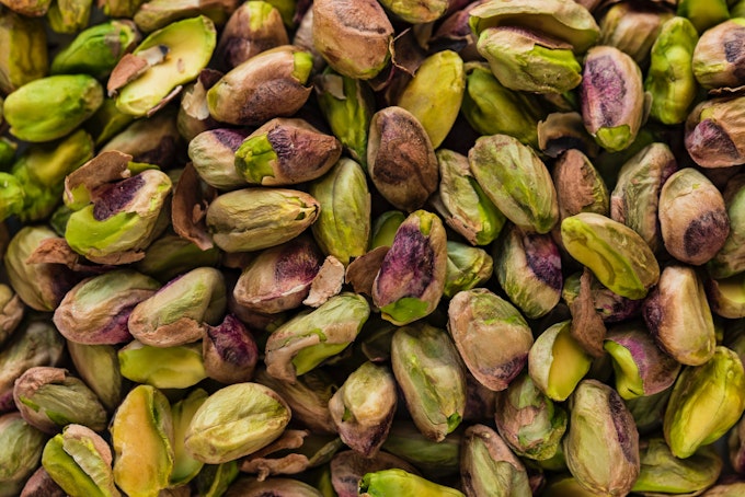 A close-up of green pistachioi nuts from above.