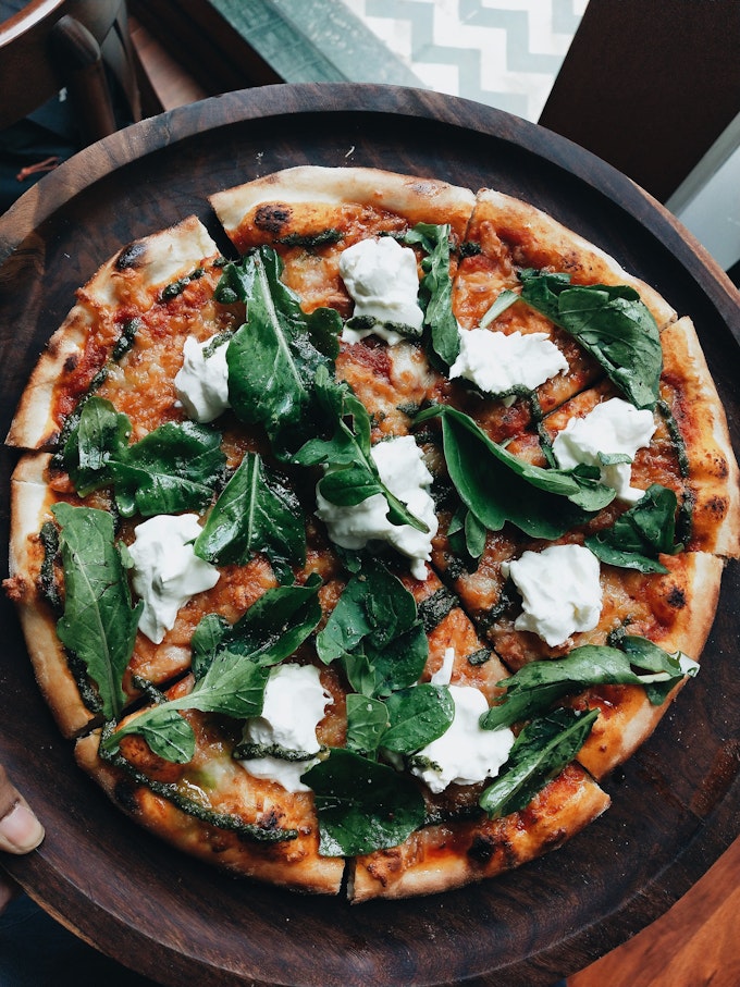 A from-above view of pizza with cheese, red sauce, and fresh greens.