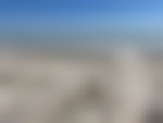 Looking toward the ocean from a boardwalk above a beach leading to the water.