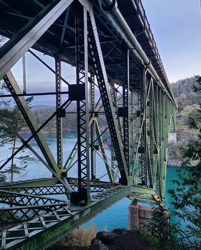 A bridge over teal water with trees along the shoreline.