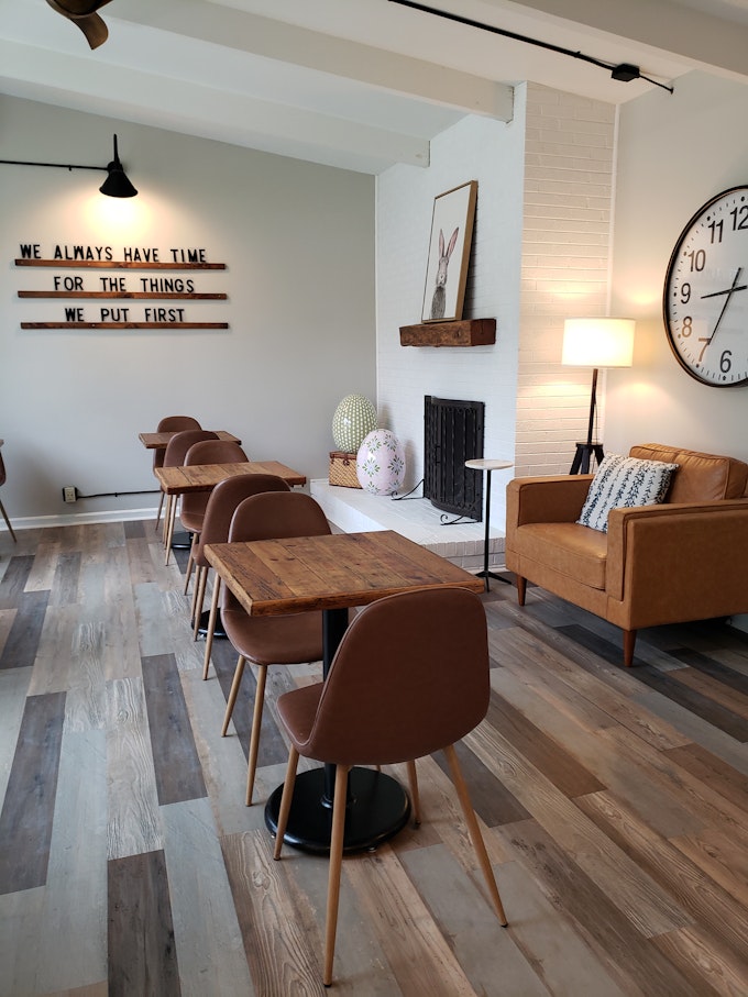 The interior of a bakery with tables, chairs, and a giant clock.