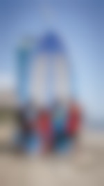 Four people standing in front of a lifeguard tower on a beach. They're wearing colorful clothes with patterns.