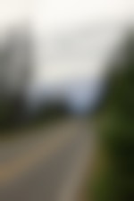 A vehicle drives away from the camera toward snowy mountains in the distance.