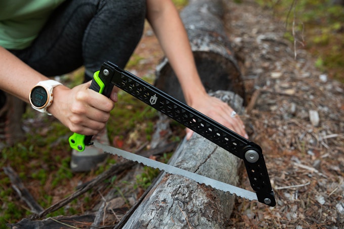 A person is using a packable saw to saw through a log.