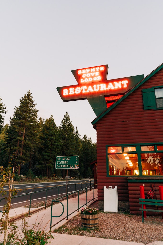 A log cabin restaurant has a neon sign that reads 