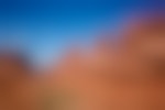 A series of tall rock structures reach out of red rock cliffs in a desert.