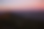 A pink and purple sunrise or sunset over a green mountain during a North Carolina hike.