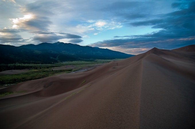 Tall sand dunes fill the right half of the image. Mountains fill the left.