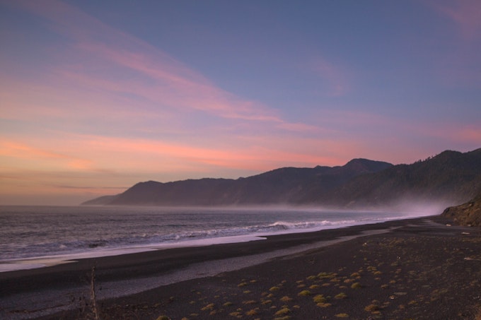 A coastline stretches into the distance where mountains rise from the sea.