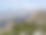 A tree-covered mountains overlooks a misty valley.